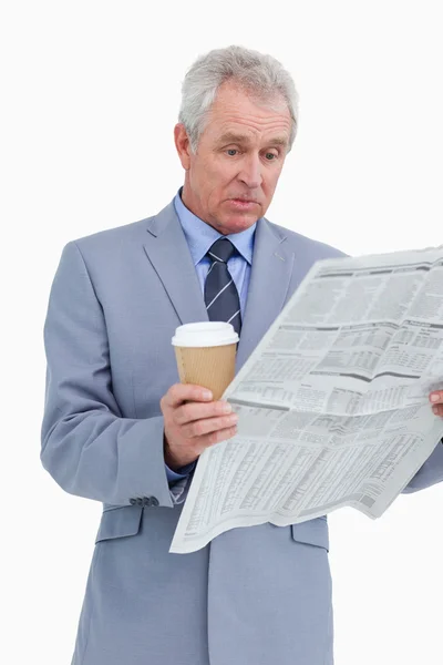 Förvånad mogna detaljhandlare med nyheter papper och papper kopp — Stockfoto