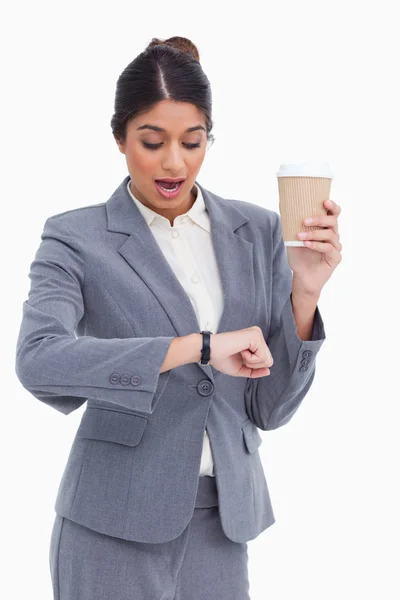 Shocked female entrepreneur with paper cup looking at her watch — Stock Photo, Image