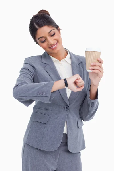 Улыбающаяся предпринимательница с бумажной чашкой, смотрящая на часы — стоковое фото