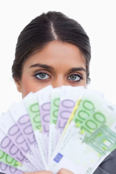 Close up de empresária escondendo seu rosto atrás de notas bancárias — Fotografia de Stock