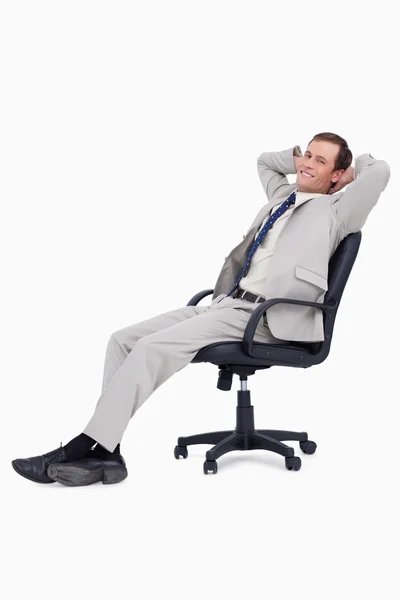 Vista lateral de un hombre de negocios sonriente recostado en su silla — Foto de Stock