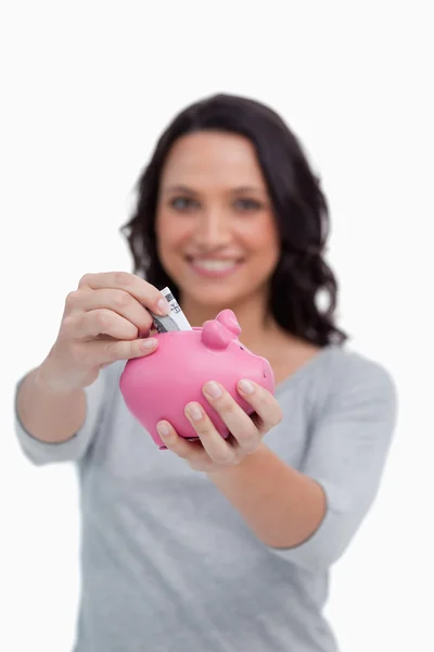 Dinheiro sendo colocado no banco porquinho por mulher — Fotografia de Stock