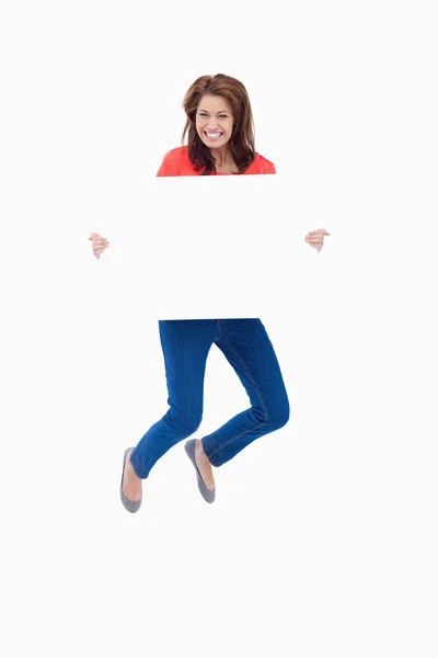 Excited teenager jumping while holding a blank poster — Stock Photo, Image