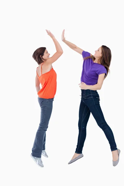 Two teenagers jumping while trying to join their hands — Stock Photo, Image