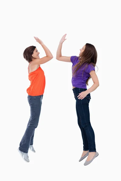 Two teenagers which are giving a high-five while jumping — Stock Photo, Image