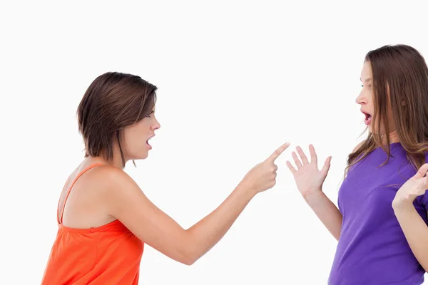 Девочка-подросток резко указывает пальцем на свою удивленную подругу — стоковое фото