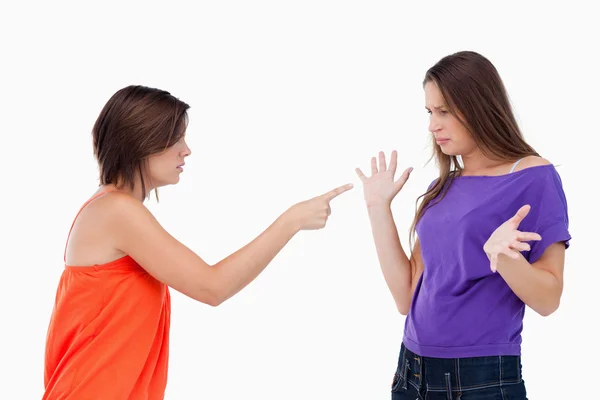 Teenage girl accusing her friend while pointing finger at her — Stock Photo, Image