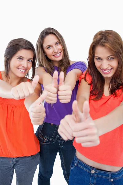 Three teenagers standing against a white background and showing — Stock Photo, Image