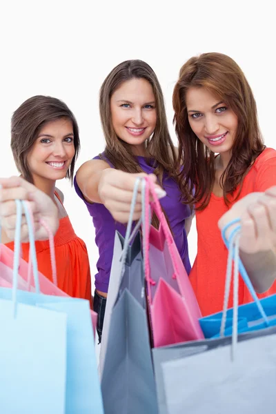 Lächelnde junge Frauen zeigen ihre Einkäufe vor dem Geschäft — Stockfoto