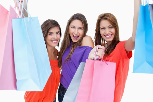 Tres adolescentes levantando sus brazos mientras sostienen sus compras —  Fotos de Stock