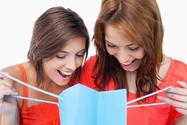 Две девочки-подростки смотрят на свои покупки против белой буквы "б" — стоковое фото
