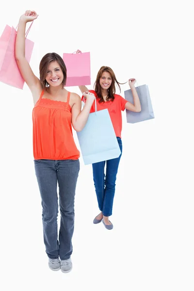 Smiling teenagers holding purchase bags in the air — Stock Photo, Image