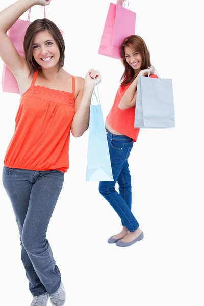 Smiling teenage girl followed by a friend and both are holding p — Stock Photo, Image