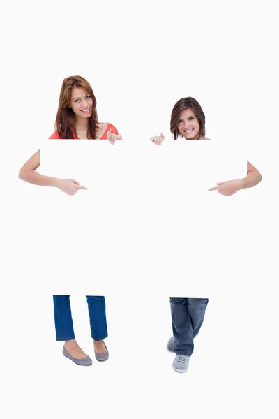 Smiling teenagers pointing their fingers at the blank poster — Stock Photo, Image