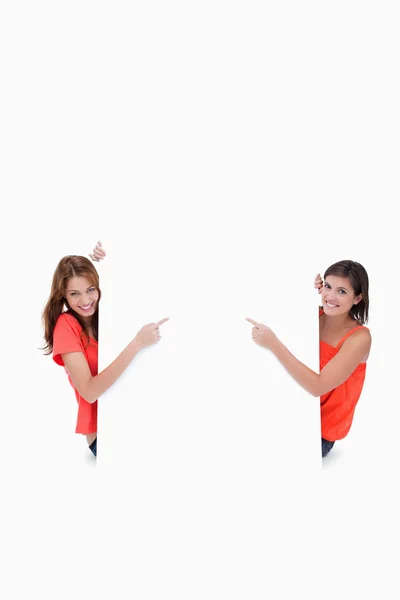 Teenage girls looking at the camera while pointing their fingers — Stock Photo, Image