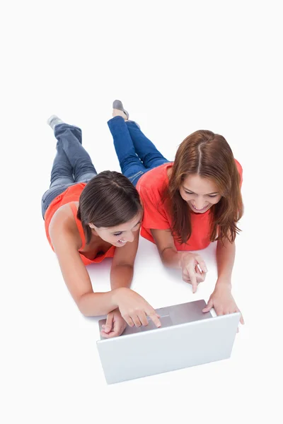 Two smiling teenagers pointing their fingers on the laptop scree — Stock Photo, Image