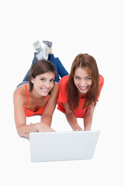 Teenagers lying down behind a laptop with legs crossed — Stock Photo, Image