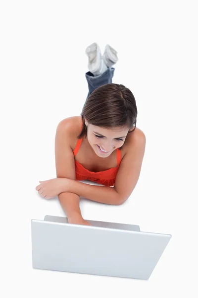 Menina adolescente inteligente deitada na frente de um laptop com pernas cro — Fotografia de Stock