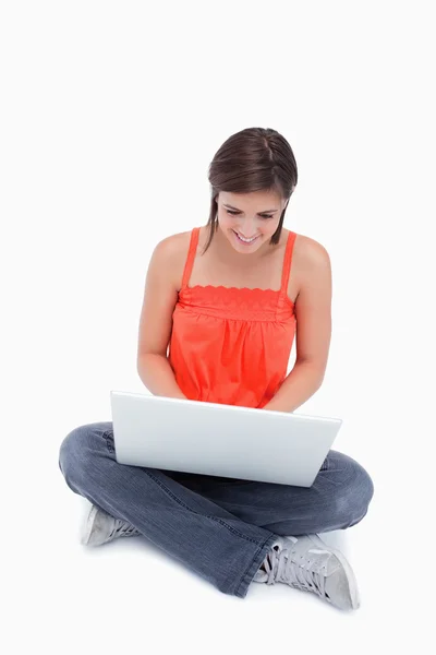 Atractiva adolescente sentada con las piernas cruzadas escribiendo en una computadora portátil —  Fotos de Stock