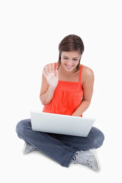 Sonriente adolescente diciendo hola a su portátil mientras está sentado cr —  Fotos de Stock