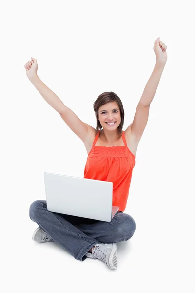 Attractive young woman sitting cross-legged and raised arms — Stock Photo, Image