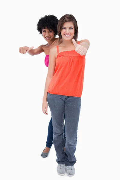 Two relaxed teenagers putting their thumbs on the side in satisf — Stock Photo, Image
