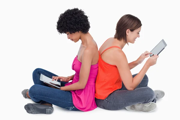 Teenage girl holding her tablet PC in the air while a friend is — Stock Photo, Image