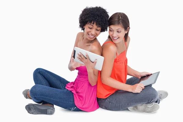 Lachen tieners op zoek op een tablet pc zittend Kruis-le — Stockfoto