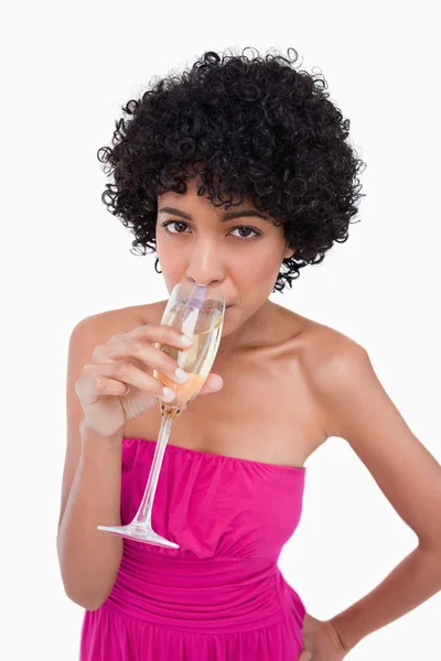 Young woman drinking a glass of champagne against a white backgr — Stock Photo, Image