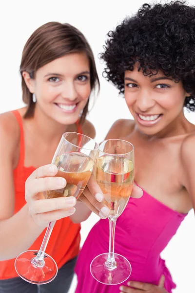 Glazen witte wijn wordt gelukkig rinkelde door twee jonge vrouwen — Stockfoto