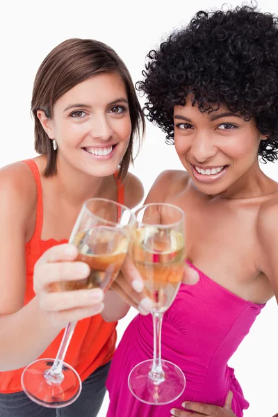 Jonge vrouwen hun glazen witte wijn rammelende glimlachen — Stockfoto