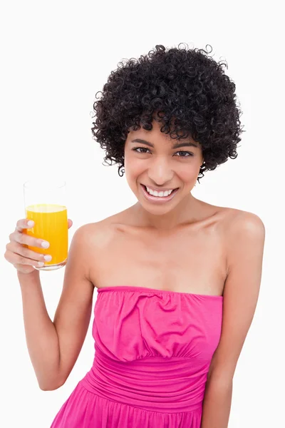 Nuori hymyilevä nainen, jolla on lasillinen appelsiinimehua — kuvapankkivalokuva