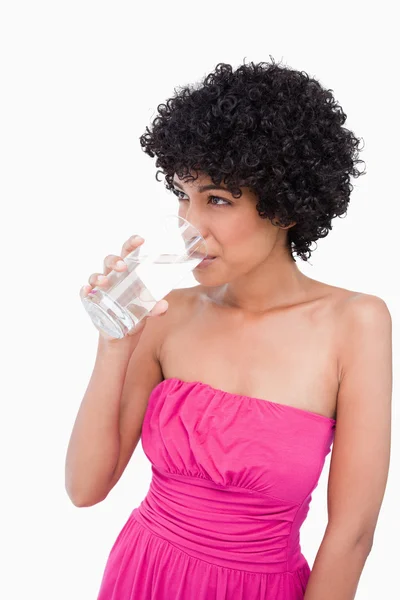 Adolescente mirando hacia un lado mientras bebe un vaso de agua — Foto de Stock