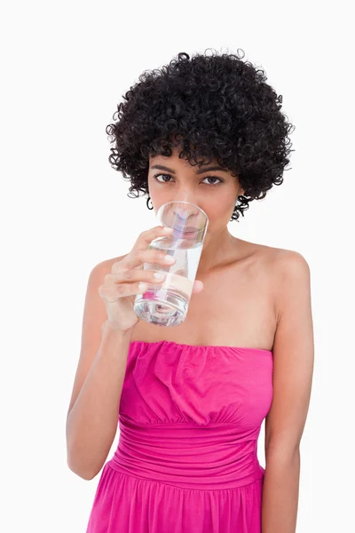 Mujer joven mirando hacia adelante mientras bebe un vaso de wat — Foto de Stock