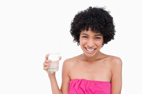 Teenager showing a beaming smile while holding a glass of water — Stock Photo, Image