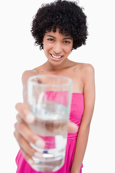 Teenager holding a glass of water in front of her while smiling — Stock Photo, Image