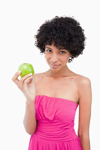 Jovem mulher atraente mostrando uma maçã verde enquanto olha para o th — Fotografia de Stock