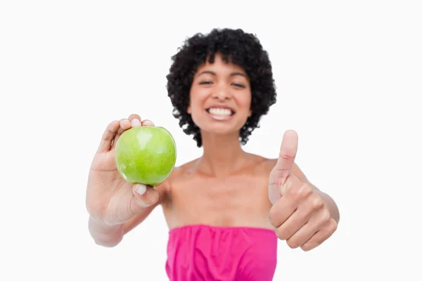 Lachende tiener holding een groene appel en haar duimen ophangen van — Stockfoto