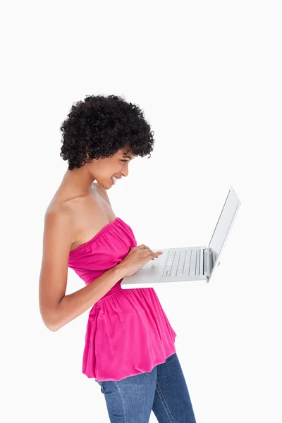 Attractive teenager standing upright while holding a laptop — Stock Photo, Image