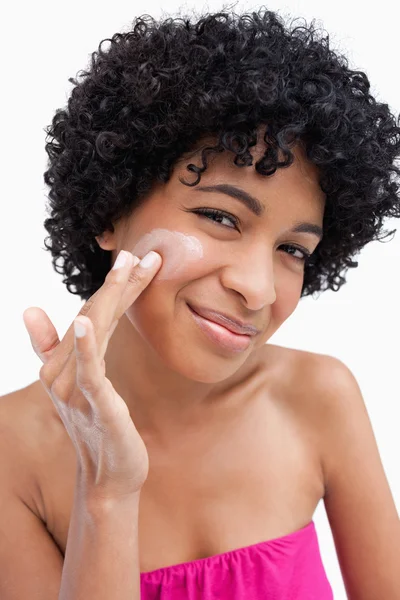 Smiling woman putting some cream on her face — Stock Photo, Image