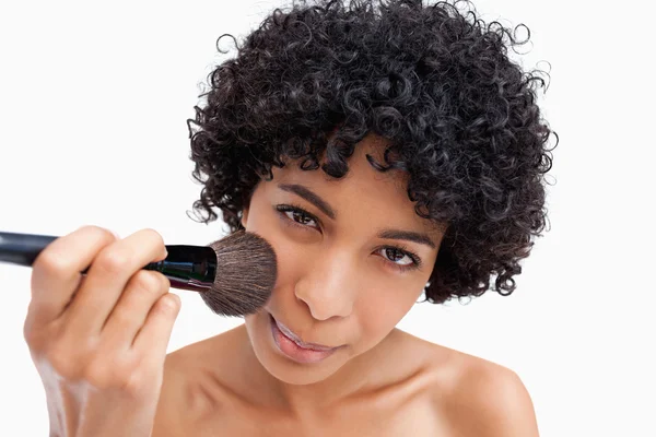 Jovem mulher aplicando blush natural em seu rosto — Fotografia de Stock