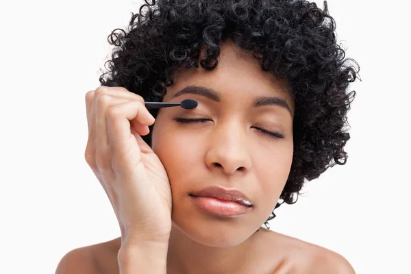 Young woman closing her eyes while applying eye-shadow — Stock Photo, Image