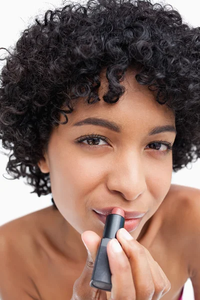 Young woman looking at the camera while applying lipstick — Stock Photo, Image