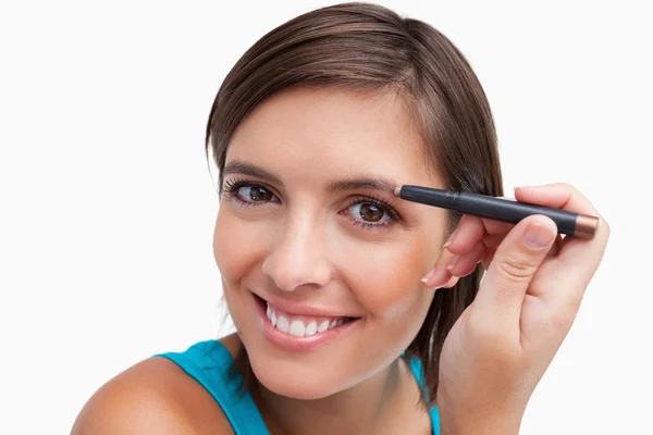 Jovem fêmea usando um lápis de sobrancelha para maquiagem — Fotografia de Stock