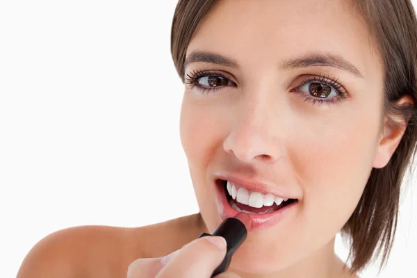Smiling teenage girl applying make-up while putting on lipstick — Stock Photo, Image