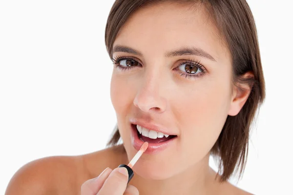 Adolescente bonita usando uma escova de lábios para aplicar gloss — Fotografia de Stock