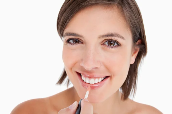 Adolescente sonriendo mientras aplica brillo de labios con un cepillo de labios — Foto de Stock