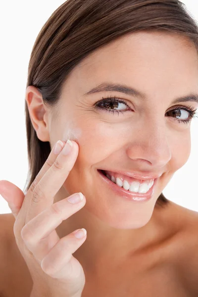 Aantrekkelijke tienermeisje moisturizer crème op haar gezicht te zetten — Stockfoto