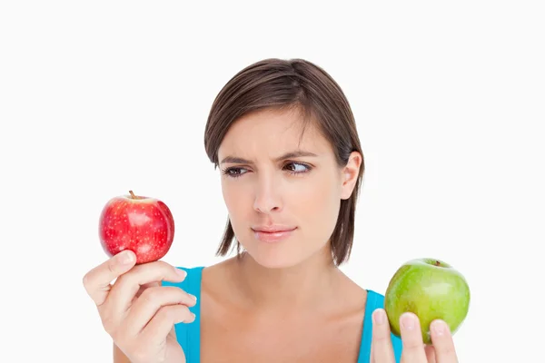 Teenage holding two apples and looking at the red one — Stock Photo, Image