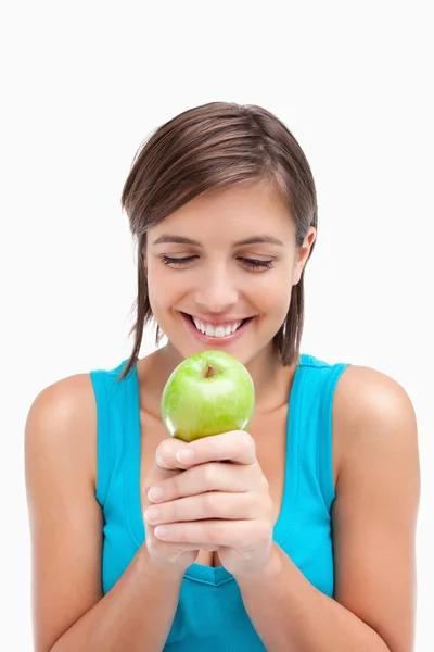 Улыбающийся подросток смотрит на зеленое яблоко, положенное ей на руки. — стоковое фото